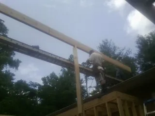 Carpenter setting a ridge beam over a new addition frame — Ice Dam Removal by Roofing Brothers in Lakeview